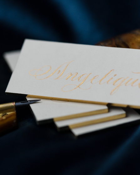 Ein Stapel Platzkarten mit goldener Kalligrafie beschriftet
